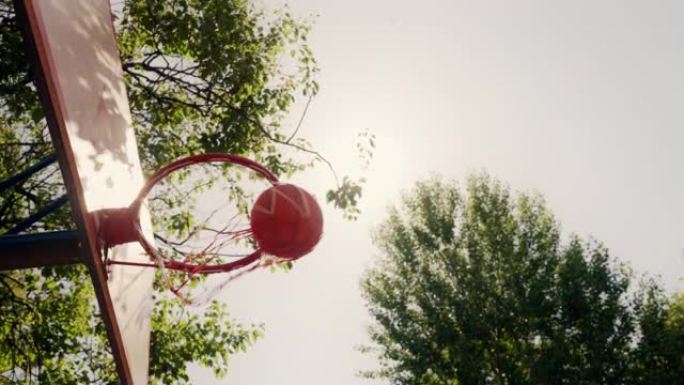 篮球在美丽的自然采光下从篮筐坠落，晴天
