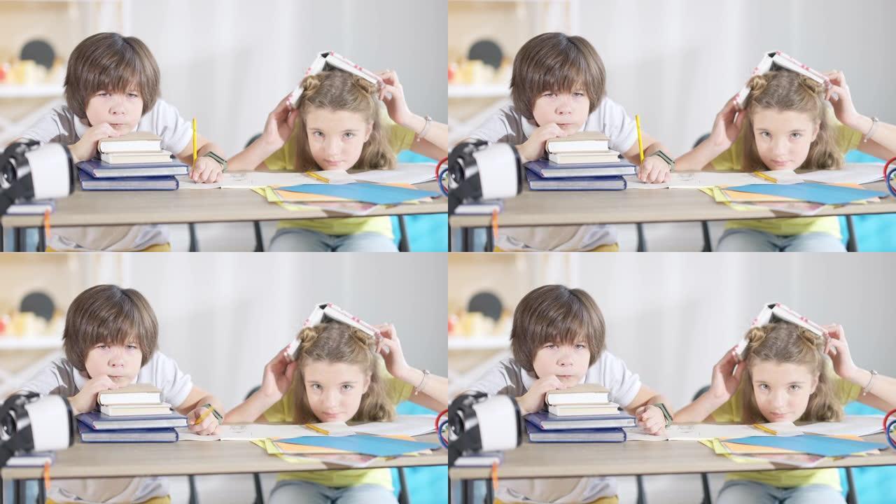 不高兴的高加索男孩和无聊的女孩坐在课桌上看着相机。不幸的孩子在学校学习的肖像。无聊和教育。