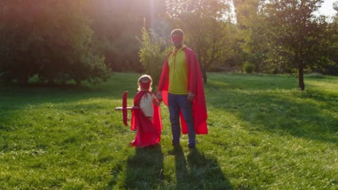 在镜头前，他们穿着超级英雄套装摆姿势的爸爸和儿子，直视公园中央的镜头