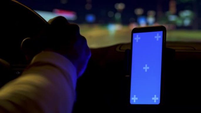 LD男子晚上在智能手机导航的帮助下在城市开车