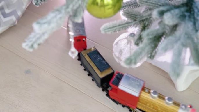 圣诞火车在带有礼品袋和礼物的圣诞树下行驶