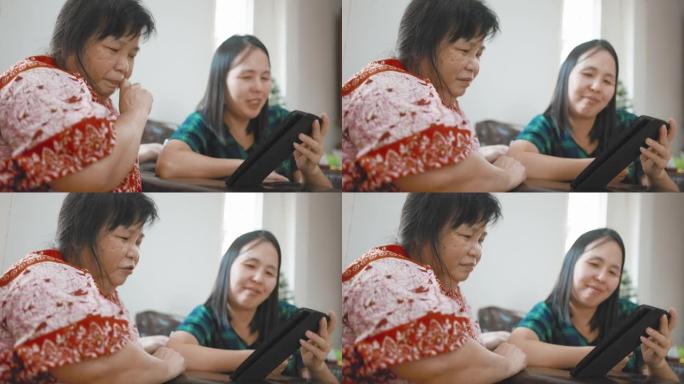 微笑的亚洲女性和她的母亲使用平板电脑