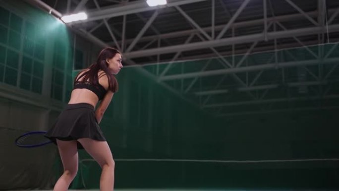 年轻的女运动员在室内球场打网球，跑步和击球，慢动作射击，室内全长肖像