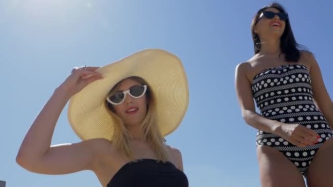 两个年轻漂亮的女孩穿着比基尼在海滩上玩得很开心