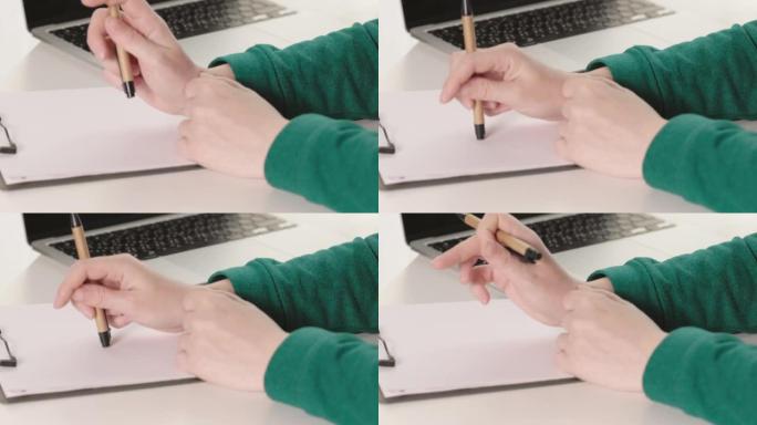 女性双手绿色袖子手握笔准备书写纸质文件书桌
