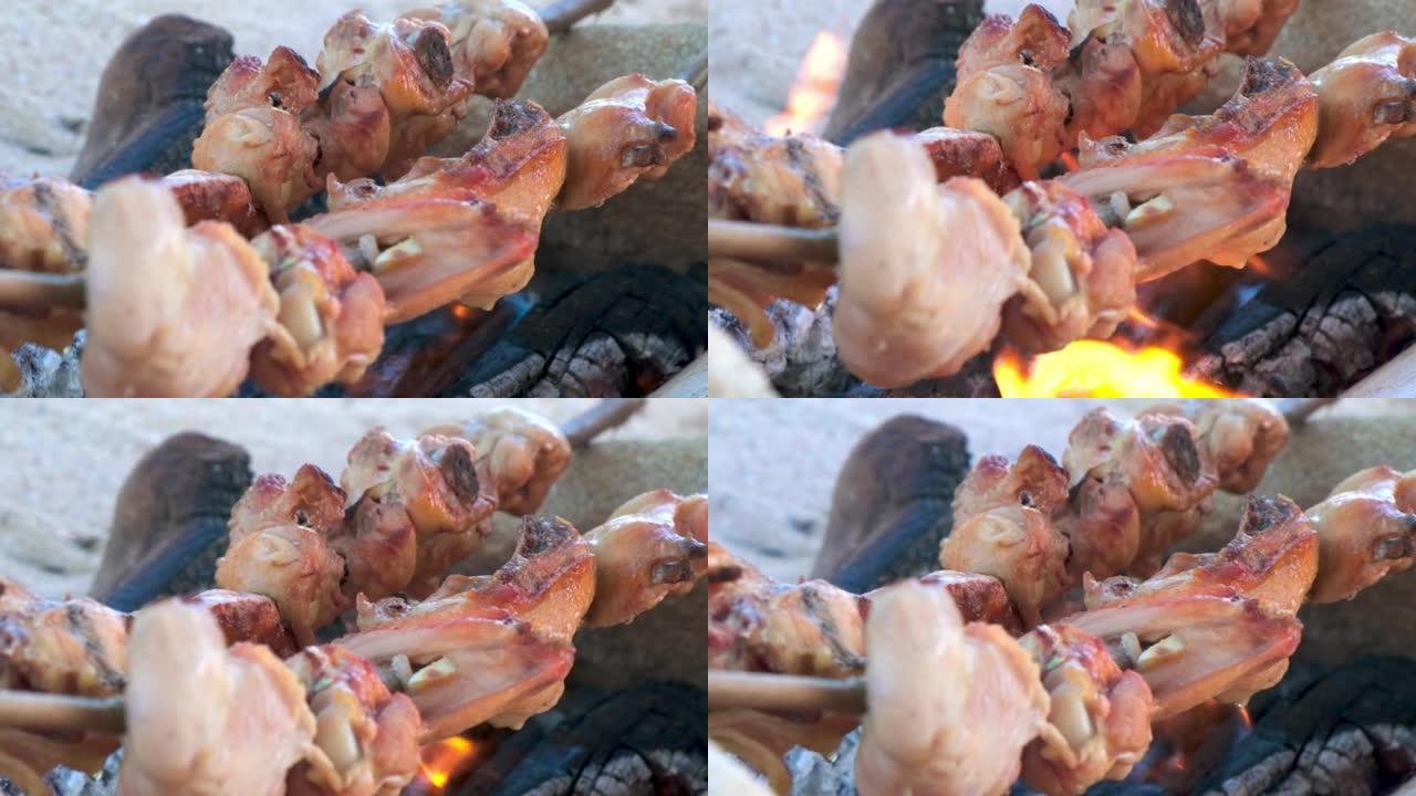 开胃脆皮鸡是在火刑柱上煮的。海滩上的野生烹饪，野营烹饪，烧烤棒，沙滩上的篝火，特写侧视图
