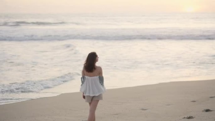 日落时在海滩上散步的女人
