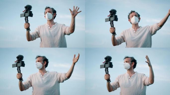 戴着口罩的男子在海洋附近与手持摄像机交谈