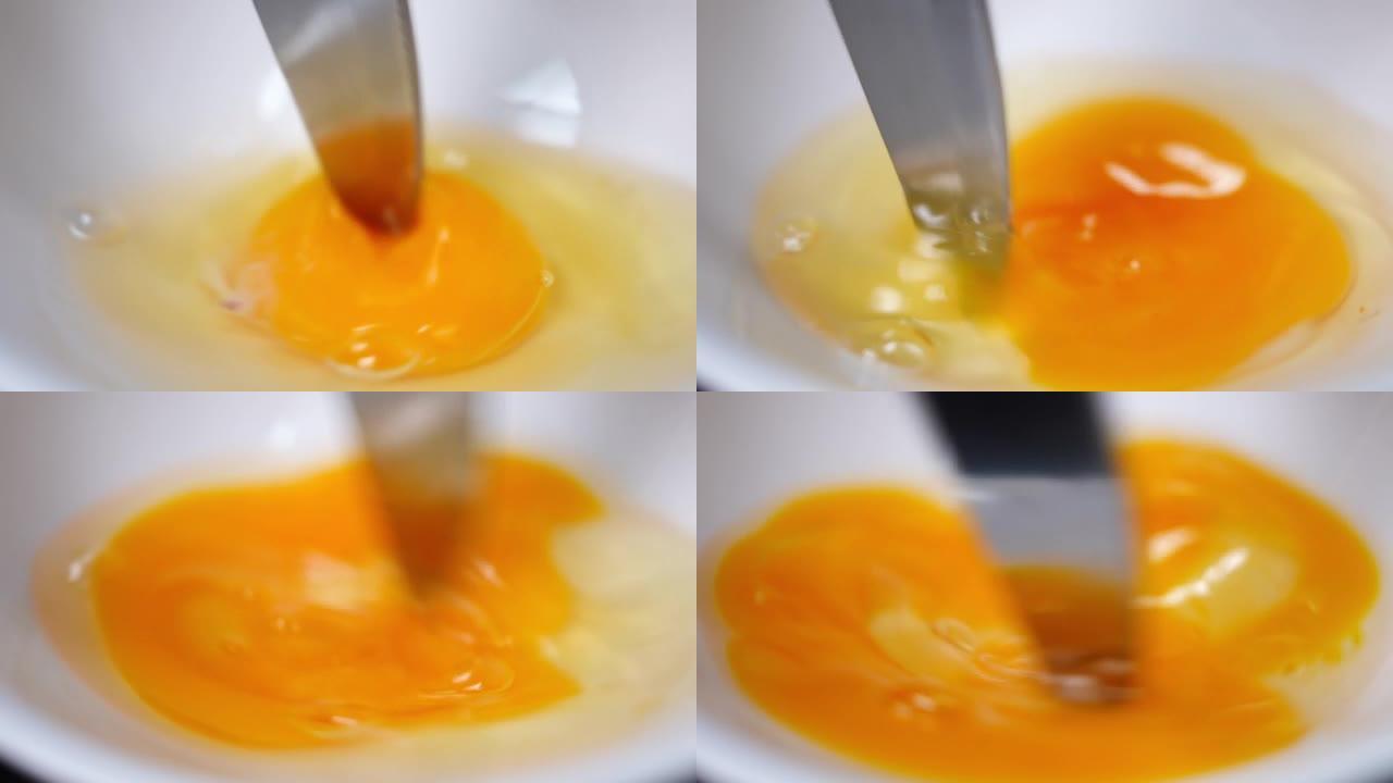 近距离刀以慢动作敲打蛋清和蛋黄。厨房白碗中鸡蛋部分混合的过程。