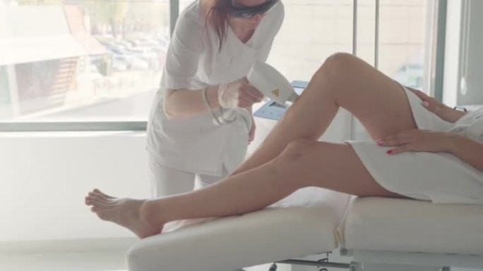 女人在当代诊所做现代激光脱毛，美容师和医疗办公室的女性客户