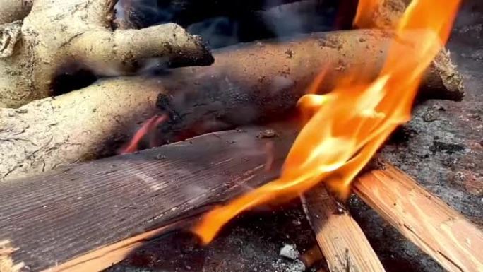 慢动作视频，特写燃烧的棍子为烧烤准备火。最近用燃烧的木头点燃了火