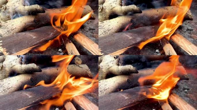 慢动作视频，特写燃烧的棍子为烧烤准备火。最近用燃烧的木头点燃了火