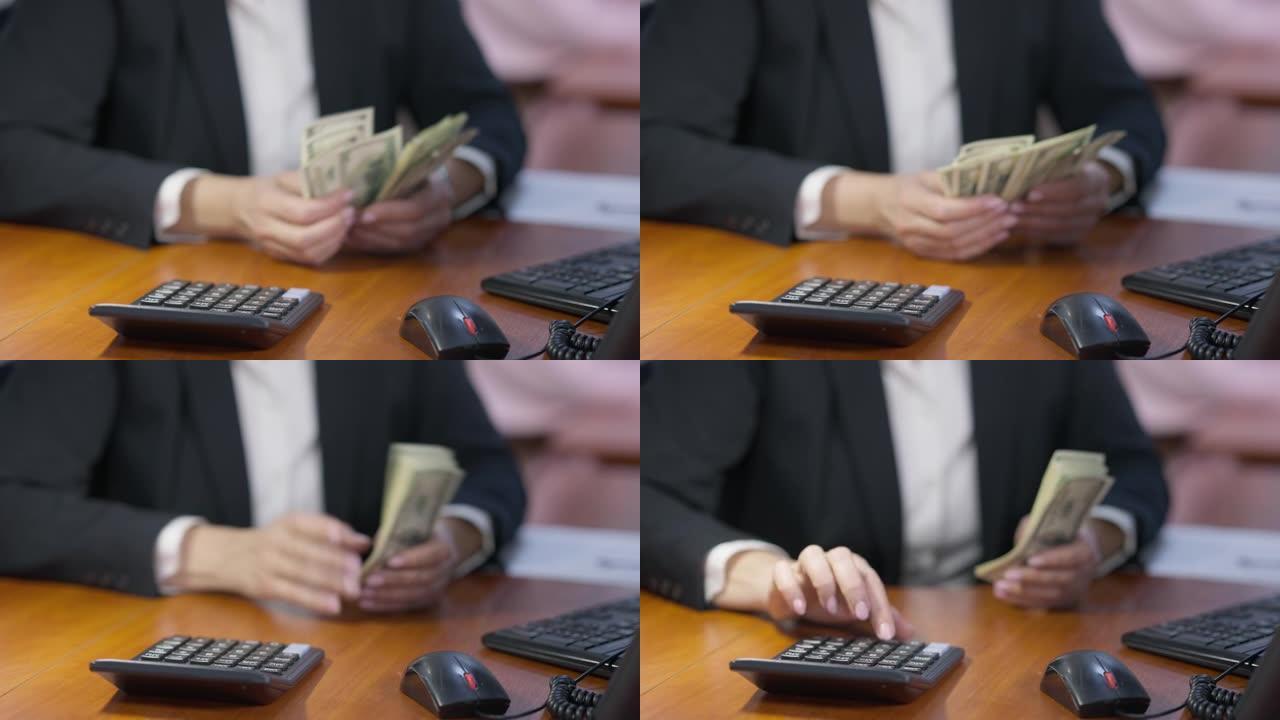 办公室桌子上计算器的特写镜头，模糊的女性手在后台数钱。面目全非的富有女商人在室内工作场所计算美元。成