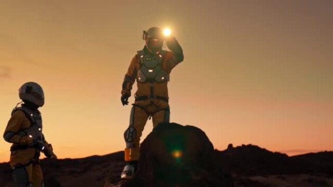 火星上的两名宇航员。在黄昏或黎明探索外星球。攀登岩石山