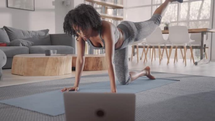 非裔美国女运动员在瑜伽垫上锻炼。家庭锻炼