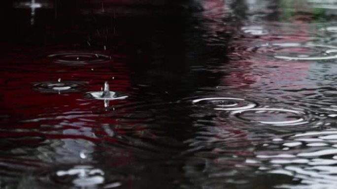 雨滴以慢动作落入水坑中。雨水淹没了城市的街道。雨滴落在沥青上，暴风气候问题全球变暖