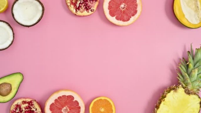 夏季热带框架由柔和的粉红色背景上的异国水果制成。创意复制空间。平放停止运动