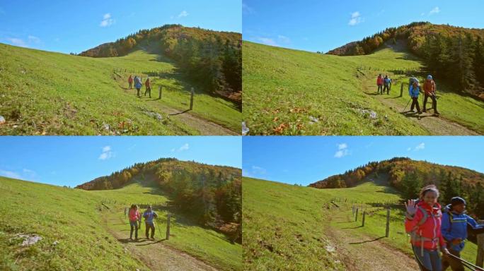 CS四名徒步旅行者沿着阳光明媚的牧场沿着山路行走
