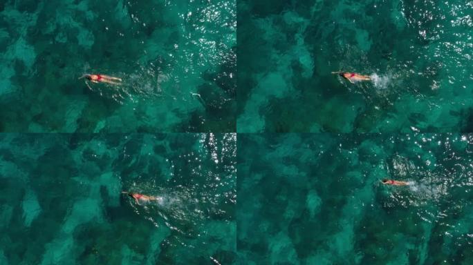 空中无人机拍摄了一名在绿松石水中游泳的妇女