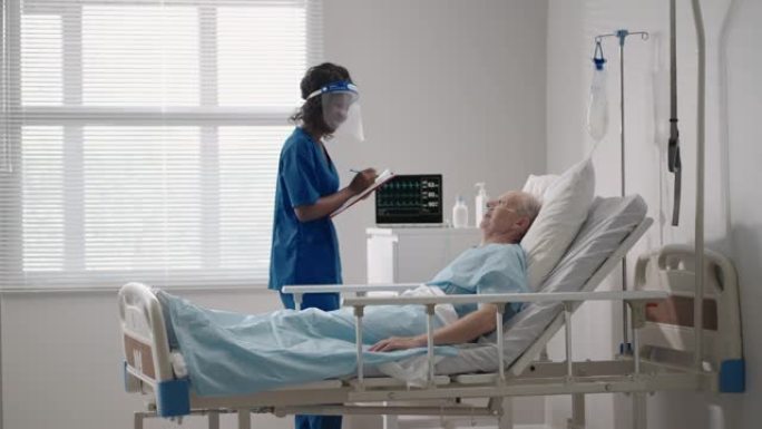 一名黑人女性心脏病专家医生正在与一名躺在病床上的老人患者交谈，讨论康复后的康复。传染病神经科医生讨论