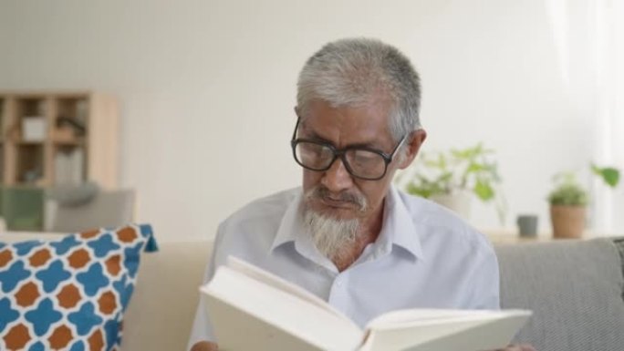 亚洲资深老人白发老人在家坐在沙发上看书