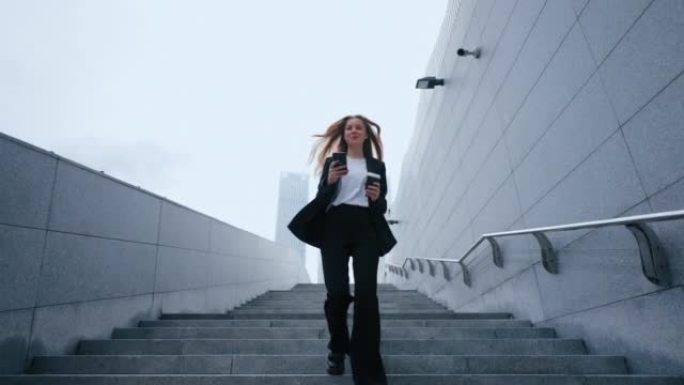 穿着黑色西装的自信年轻女子正走在市中心的楼梯上