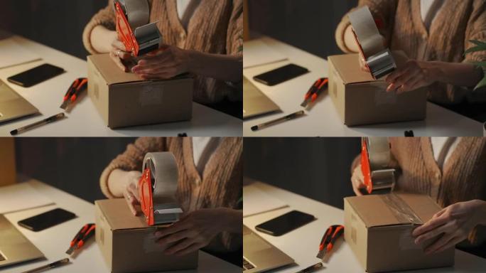 女人晚上在工作台上用卷式胶带分配器密封纸箱，送货服务