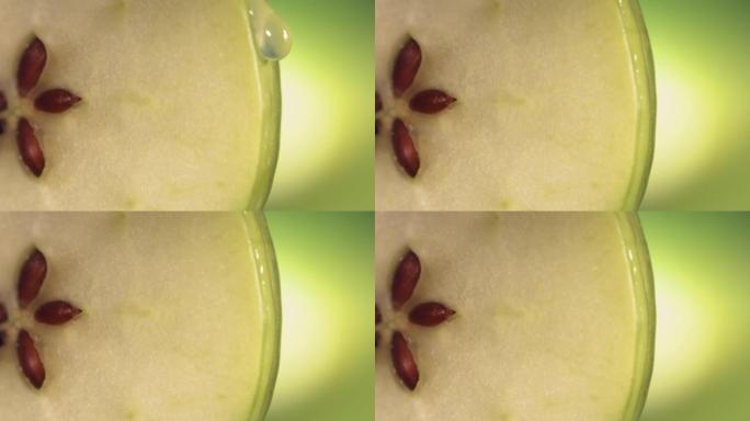 一滴水顺着成熟多汁的青苹果片的表面流下来。慢动作4K