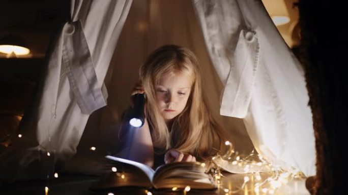 小女儿晚上不睡觉，用毯子躺在小屋里的魔法童话看书