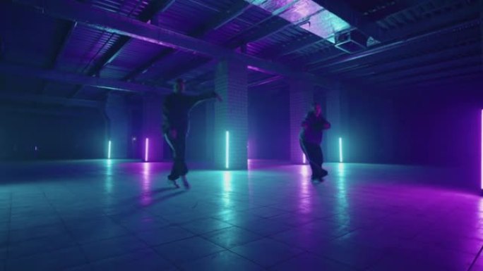 两位霓虹灯中的嘻哈舞者以蓝色和紫色一起跳舞。