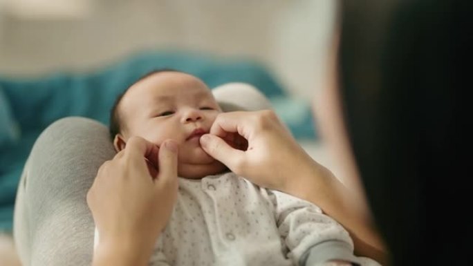 微笑的亚洲妈妈和她可爱的新生男婴玩耍