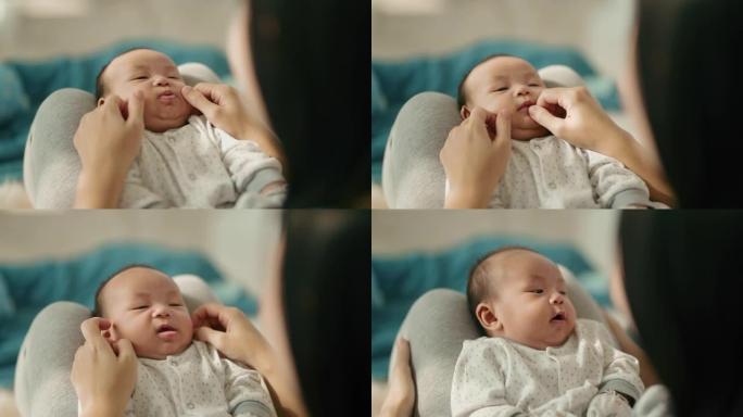 微笑的亚洲妈妈和她可爱的新生男婴玩耍