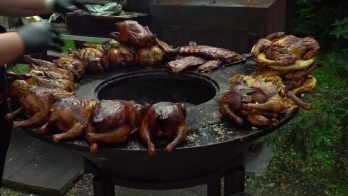 厨师翻转鸡肉烤架。街头美食节上的烤鸡。烤肉店鸡，烤鸡和熏鸡在烤架上