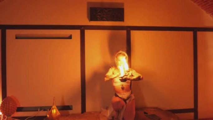 长镜头拍摄的是一个异国情调的火舞者在一间被火焰照亮的房间里