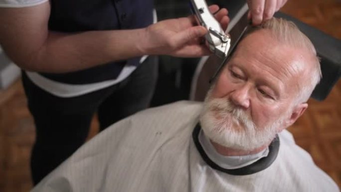 在一家现代化的理发店里，专业的男发型师用剃刀和梳子为年长的顾客理发和造型