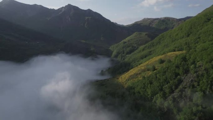 空中无人机在群山环绕的山谷中拍摄低矮的云层