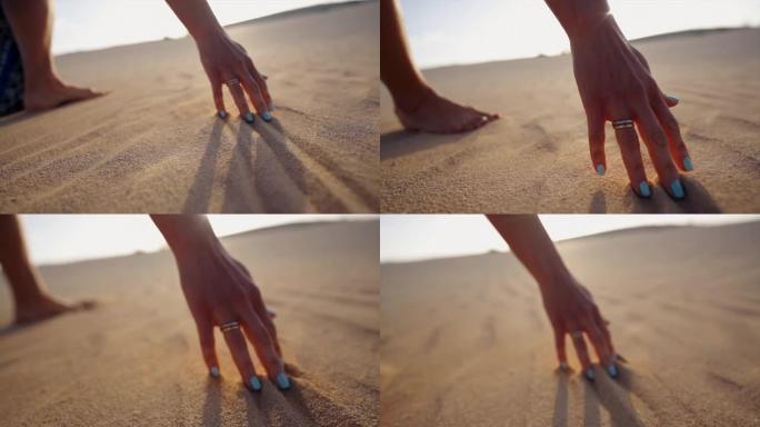 一个女人用手指穿过沙子的细节镜头