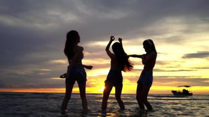 4k剪影组亚洲女子在夏季日落时在热带岛屿海滩上一起跳舞。