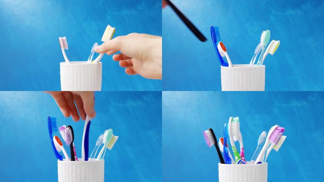 一只手将不同的多色牙刷放入蓝色背景上的杯子特写镜头中。4k原始视频，摄像机运动流畅。