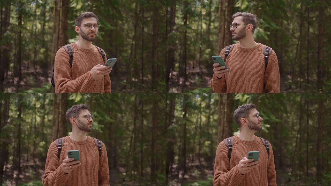 一个背着背包和手机的男性旅行者正在森林中穿行。全球定位系统、导航仪、在线地图、位置搜索。使用手机上的