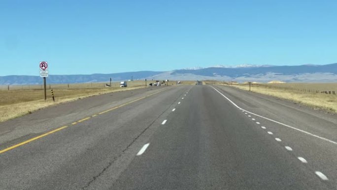在晴朗的晴天，怀俄明州沿80号州际公路驶过空旷的田野的前车镜头