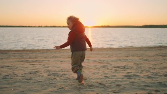 微笑的小男孩在日落时分在海滩上奔跑，在大自然中玩耍