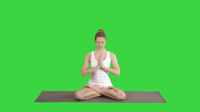 瑜伽姿势放松的女人把手放在一起，在绿色屏幕上冥想，色度键