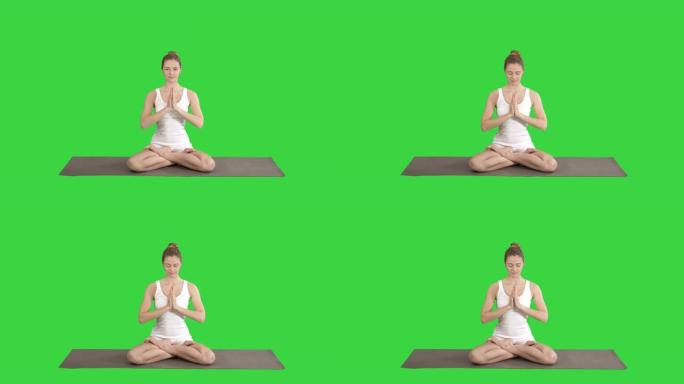 瑜伽姿势放松的女人把手放在一起，在绿色屏幕上冥想，色度键