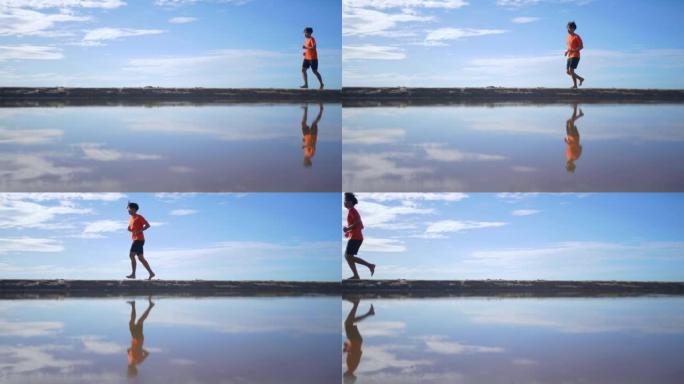 慢动作: 男子在海滩晴朗的天空上奔跑
