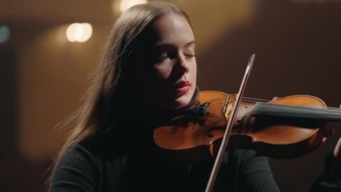漂亮年轻的女小提琴演奏者在爱乐大厅表演音乐，肖像