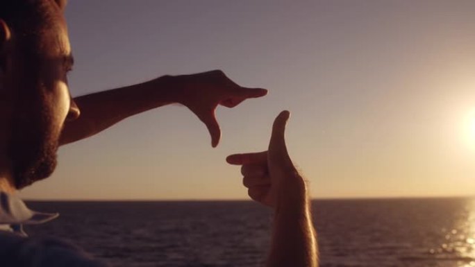 男摄影师做手指框手势拍摄美丽的海景