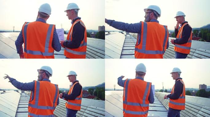 男工程师在屋顶太阳能发电厂与同事讨论