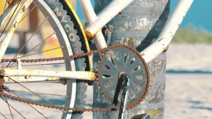 在海滩上关闭一辆生锈的旧自行车的细节照片