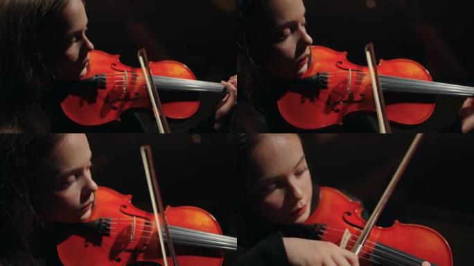 有红色小提琴的才女在音乐厅现场的交响乐团中演奏，肖像
